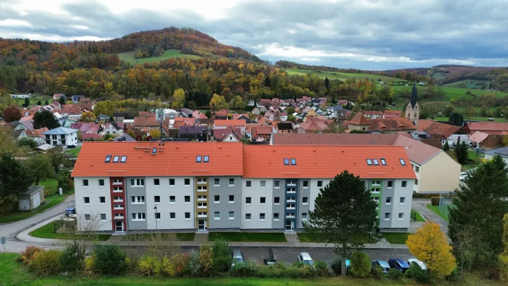 Sanierte Wohnanlage der KOWO in der Bergstraße in Geismar, Luftaufnahme mit Blick auf den Ort und die Hügellandschaft.