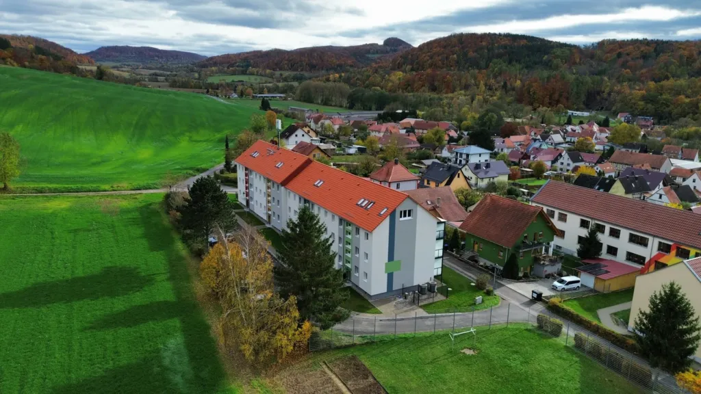 Luftaufnahme des KOWO-Wohngebäudes in der Bergstraße in Geismar, eingebettet in Ortslage und Landschaft des Obereichsfeldes.