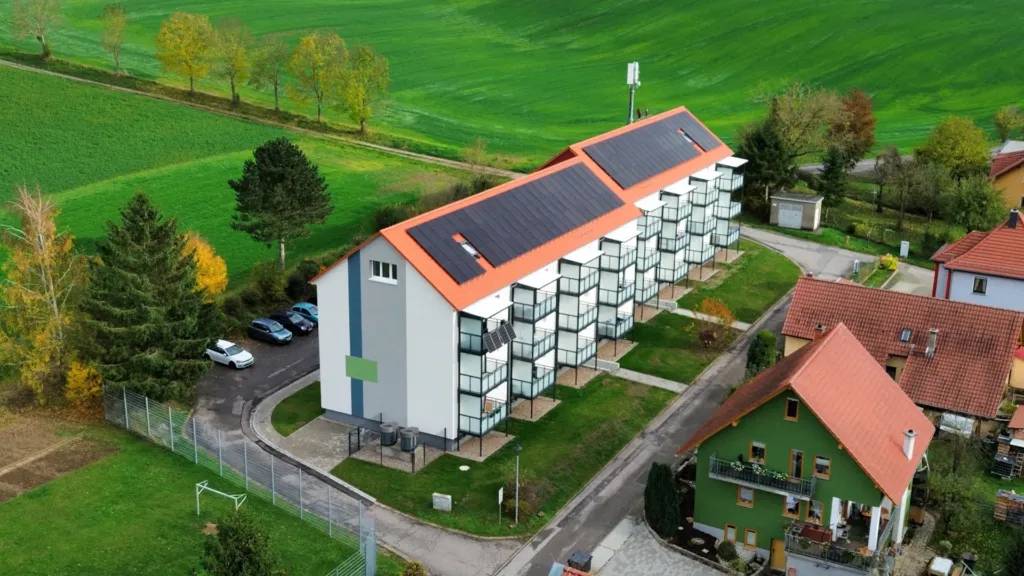 Luftaufnahme des sanierten Wohngebäudes Bergstraße in Geismar mit Balkonen und Solaranlage auf dem Dach