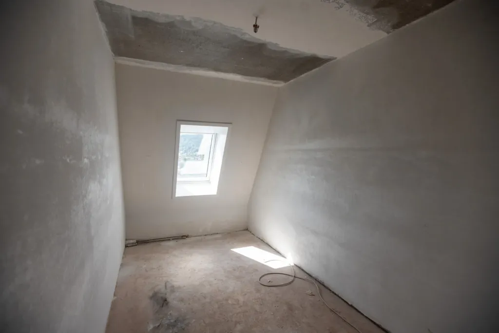 Rohbauzimmer mit Dachschräge und Fenster während der Sanierung auf den Liethen, KOWO-Neubauprojekt für Familienwohnungen