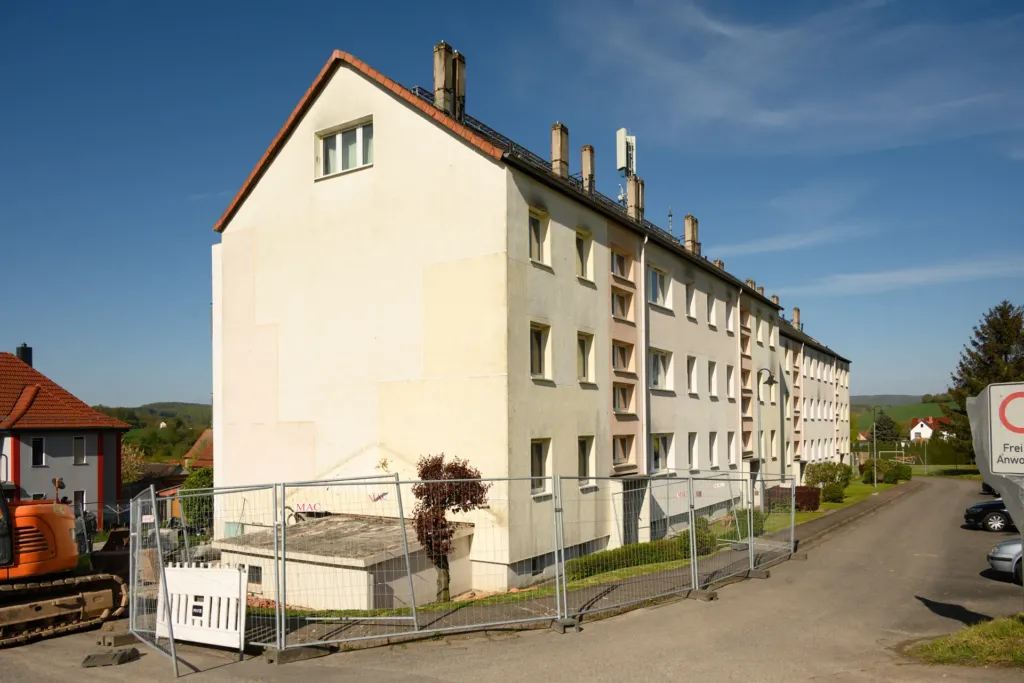Mehrfamilienhaus in der Bergstraße in Geismar, eingerüstet mit Bauzaun vor Sanierungsbeginn.