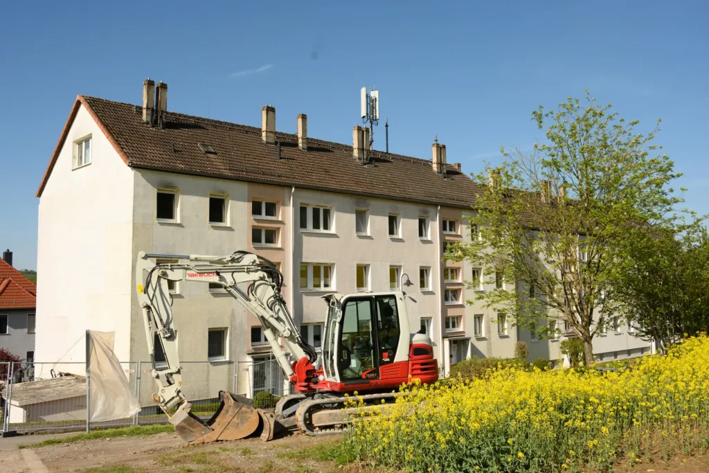 Bagger vor Mehrfamilienhaus in der Bergstraße in Geismar während Sanierungsarbeiten der KOWO Obereichsfeld.