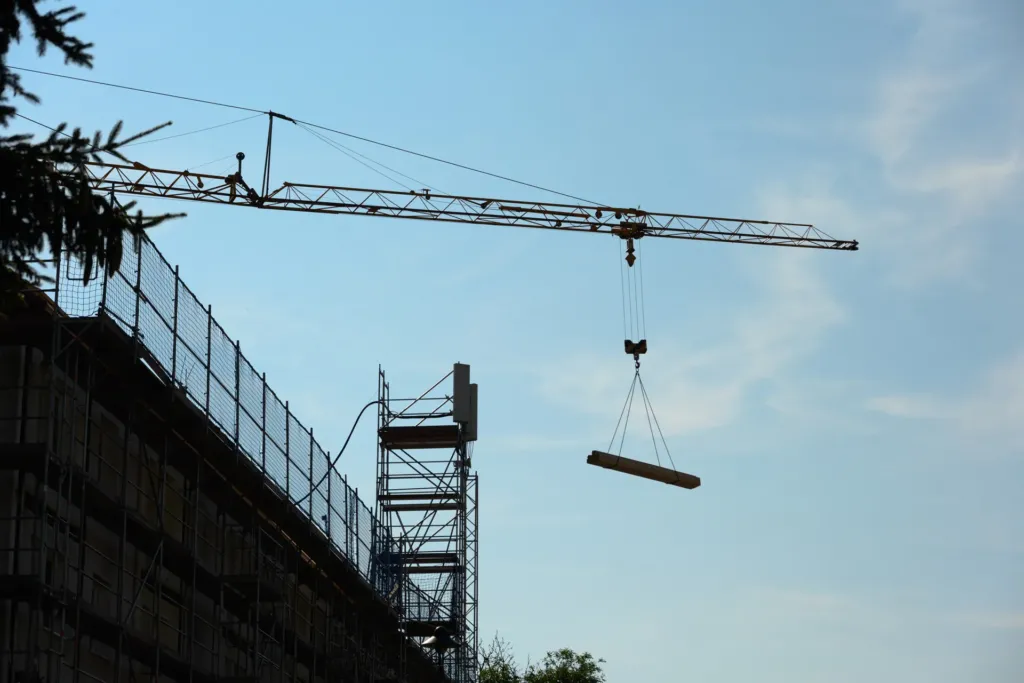 Baukran hebt Holzbalken bei Sanierungsarbeiten an der Bergstraße in Geismar, Obereichsfeld.