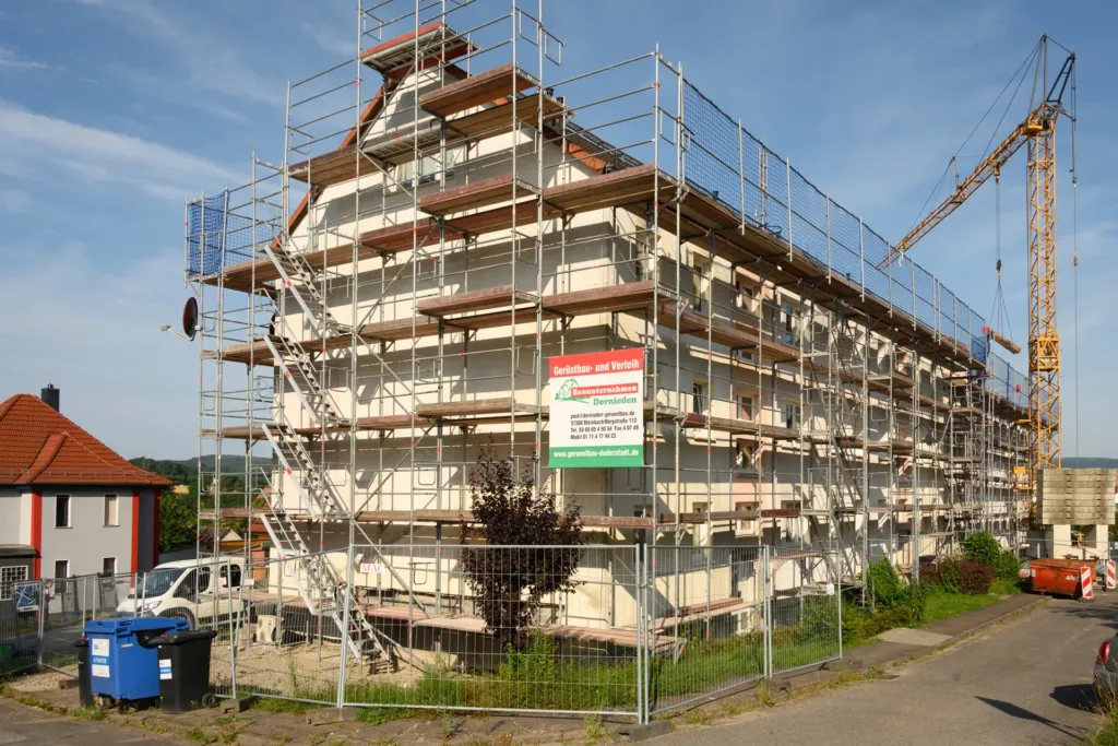 Eingerüstetes Mehrfamilienhaus in der Bergstraße in Geismar während der Fassadensanierung, mit Baukran im Hintergrund.