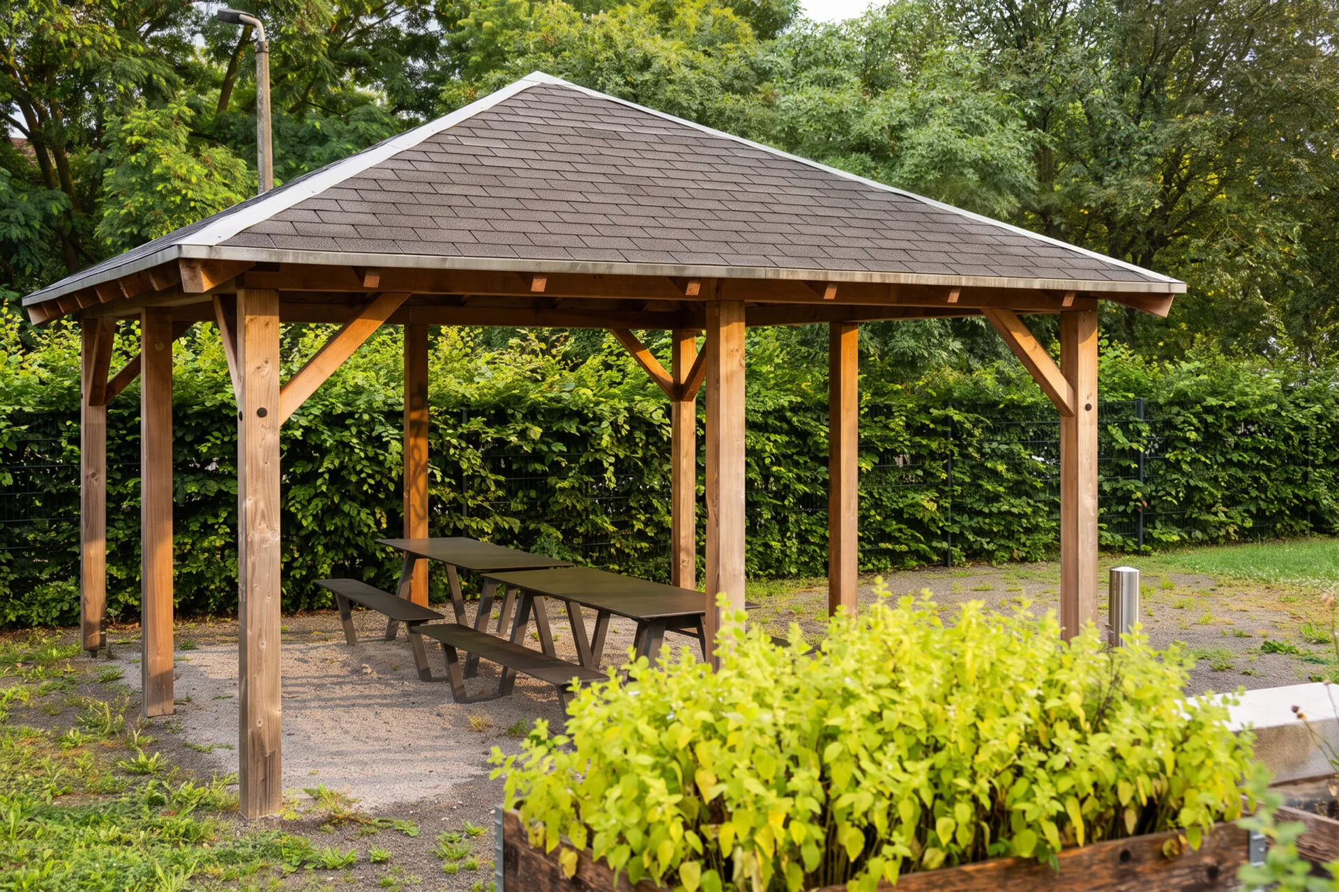 Überdachter Pavillon mit Sitzbänken im Mietergarten der KOWO Obereichsfeld, umgeben von Grünflächen