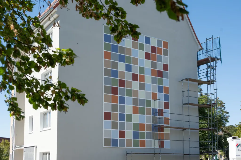 Giebelwand eines sanierten Wohnhauses auf den Liethen in Heilbad Heiligenstadt mit rasterförmigem Fassadenbild und Gerüst
