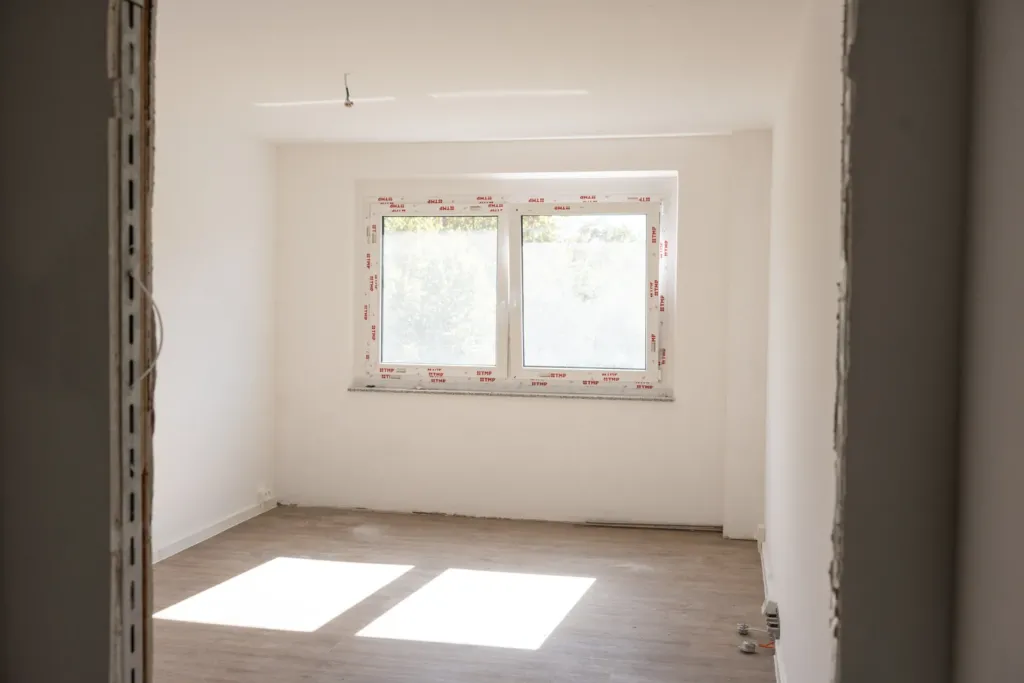 Leerer, sanierter Raum mit neuem Fenster und Holzboden in den neuen Familienwohnungen auf den Liethen in Heilbad Heiligenstadt