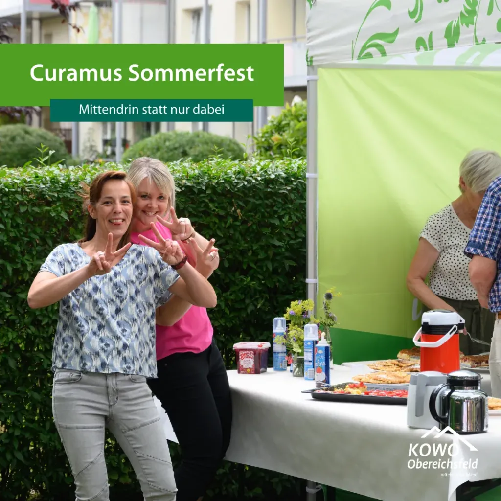 Zwei lachende Frauen zeigen Victory-Zeichen beim Curamus Sommerfest der KOWO Obereichsfeld im Freien am Buffet.