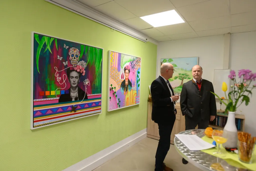 Kunstausstellung im Quartier 44: Zwei Männer betrachten Frida-Kahlo-Gemälde an bunter Wand