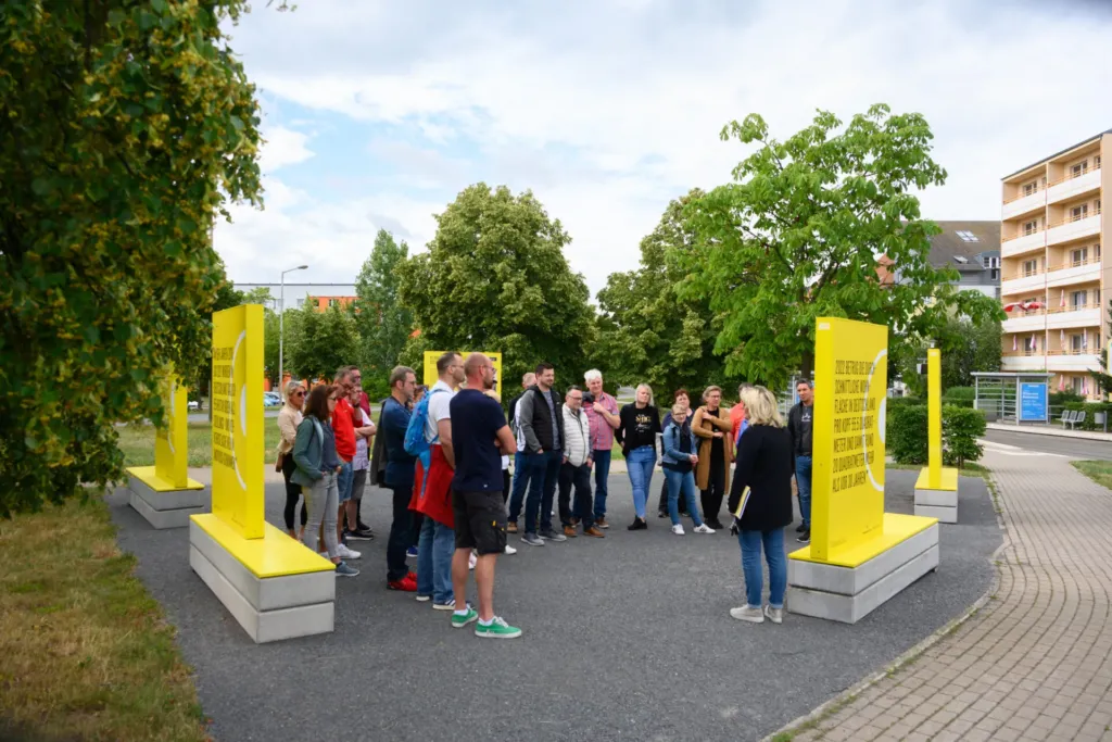 KOWO-Mitarbeiter beim Betriebsausflug zur SWG Nordhausen vor gelben Informationsstelen im Freien