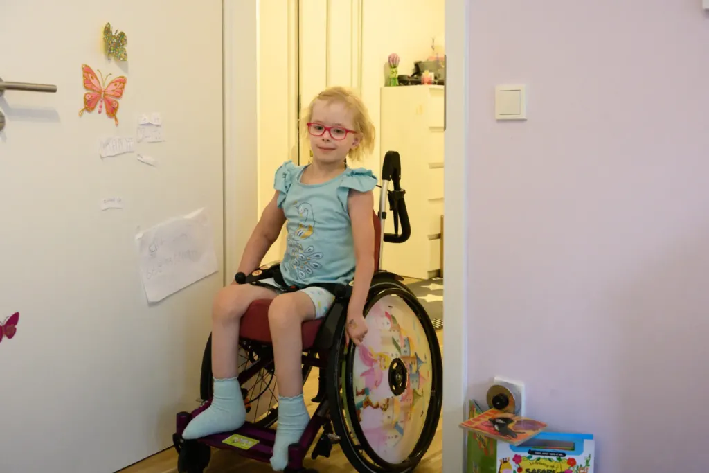 Mädchen im Rollstuhl in barrierefreier KOWO-Wohnung im Obereichsfeld an der Zimmertür