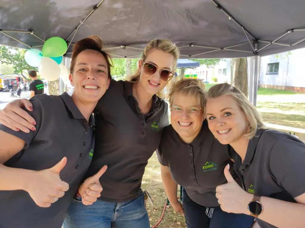 Vier lächelnde KOWO-Mitarbeiterinnen mit Daumen hoch beim Stadtteilfest Liethen in Heilbad Heiligenstadt