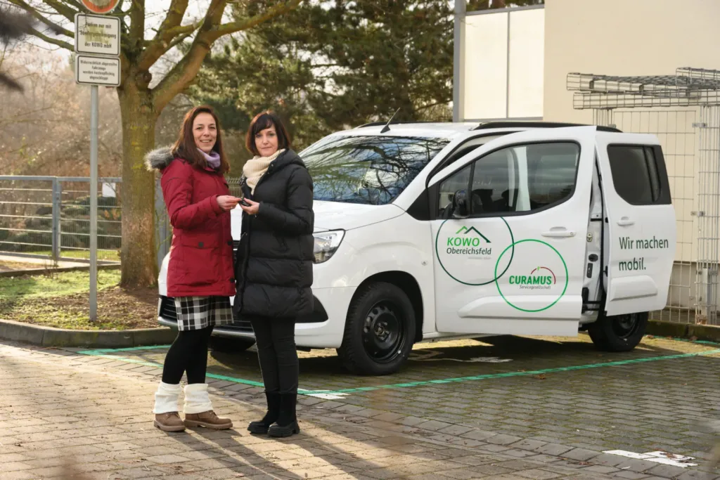 Zwei Frauen übergeben symbolisch den Schlüssel für ein KOWO-Curamus-Elektrofahrzeug im Obereichsfeld